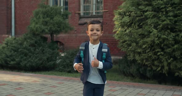 Crop View of Happy Little Boy Running and Looking To Camera. Child in School Uniform with Backpack