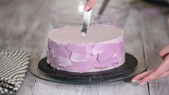 The process of decorating a cake with purple cream cover.