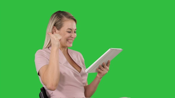 Woman Sitting Watching Tablet Pc and Smiling on A Green