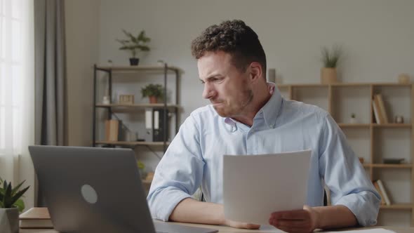 Attractive Angry Stressed Young Businessman in Shirt Sit at Desk Reading Bad Awful News in Mail
