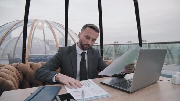 Man with Documents in Rooftop Cafe