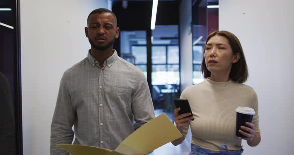 Asian businesswoman walking using smartphone going through paperwork in modern office