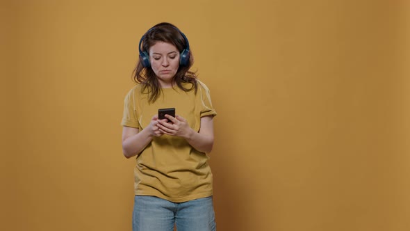 Portrait of Relaxing Woman Using Smartphone Listening to Music on Wireless Headphones Starting to