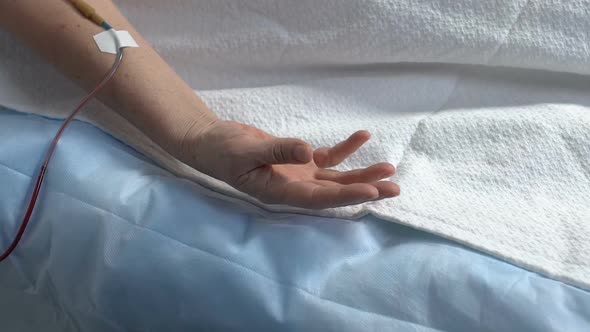 Hand of Helpless Patient Lying on Hospital Bed, Dropper in Arm, Person Dying