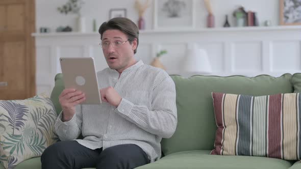 Man having Loss on Tablet on Sofa