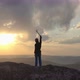 Drone Shot of a Man Standing on Top of a Rock Mountain and Joyfully Waving His Hands Holding an Ice - VideoHive Item for Sale
