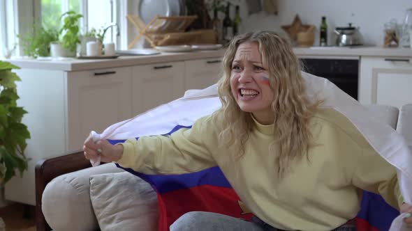 Russian Joyful Woman Sports Fan with the Flag of Russia Watches TV at Home
