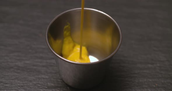 Pouring mustard into a stainless steel ramekin for dipping.