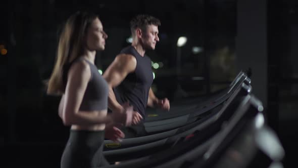 Wellness Female and Man Athlete Run on a Treadmill Two Runners Perform Aerobic Exercise and