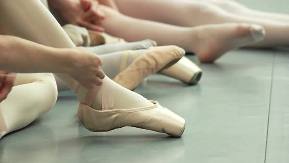 Group of Young Ballerinas Taking Off Pointe Shoes