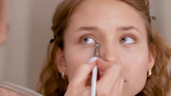 Applying Makeup. Giving the Eyes of the Young Girl's Expression. Stroke the Eye Contour with a