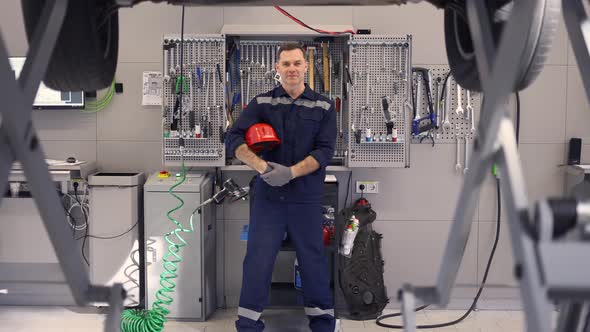 Full Length of a Car Mechanic in a Car Workshop with Equipment on the Background