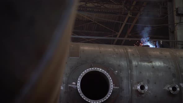 A Welder Welds a Large Pipe in a Factory