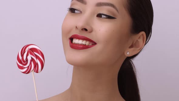 Fashion Portrait of Asian Woman with Lollipop in Studio