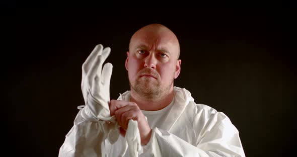 Adult Bald Man Is Putting Gloves and Overall for Protection From Viruses and Toxins, Medium Portrait