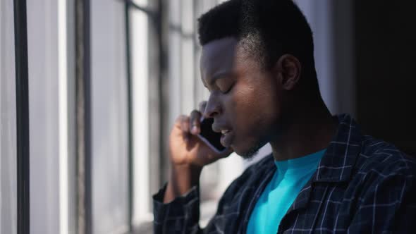 Side View Face of Confident Handsome African American Man in Sunlight Talking on Smartphone Drinking