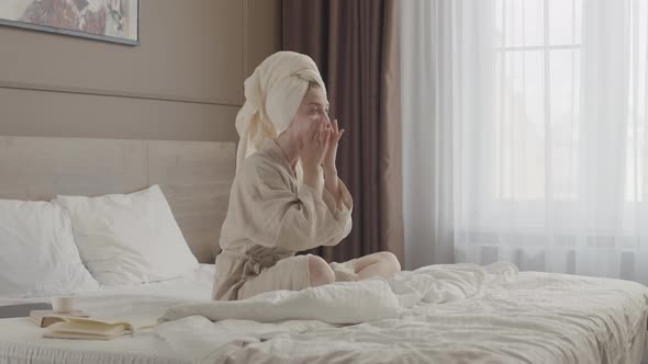 Woman with Towel on Head Applying Face Cream