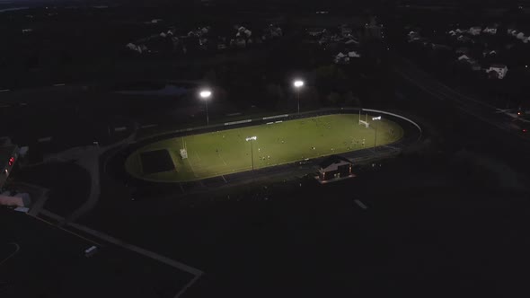 Aerial footage of a football field stadium with lights on, 4k drone