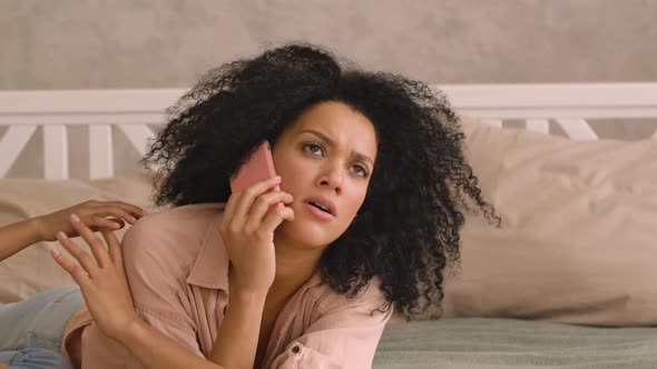 African American Woman is Talking on Smartphone Little Girl Distracts Her From Conversation