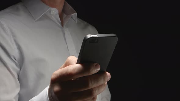 Man In White Shirt Holds A Smartphone By Hand And Touches On It