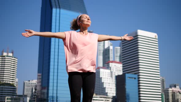 Happy Sport Woman In Wireless Earphones Raising Arms After Workout In City