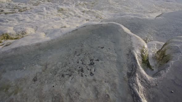 Barefoot man stands on a wet limestone surface in Pamukkale, Turkey