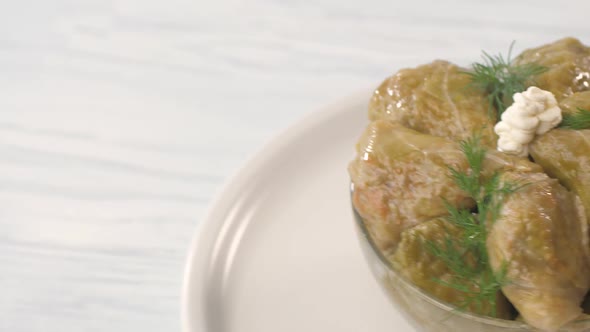 Prepared Triangular Stuffed Cabbage Decorated with Dill and Sour Cream