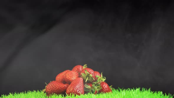 Bright Red Strawberries on Green Rotating Grass Surface Against Black Background