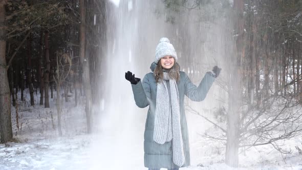 Woman Staing Snowy Forest and Throwing Handful of Snow