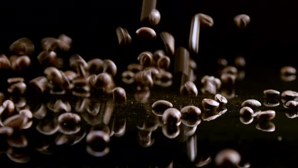 Coffee beans falling on a black mirror