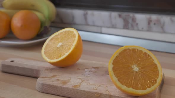 Fresh Orange Sliced In Half Moving Sideways Back And Forth On Wooden Chopping Board. - close up slow