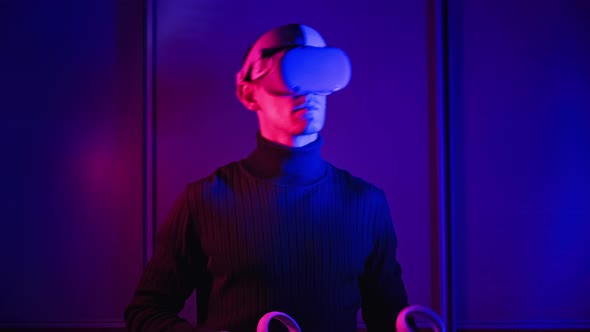 Young Man in a VR Helmet Interacts with Virtual Reality and 360 Media Content