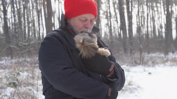 Bearded Pensioner Holds Small Puppy and Hugs Close