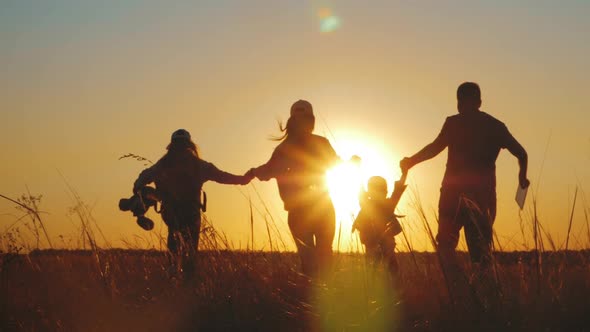 Happy Young Family Together with Two Children at Sunset. Parents Raising Baby Up in the Air. People