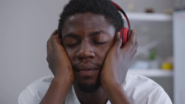 Headshot Positive Relaxed African American Doctor in Headphones Enjoying Music with Eyes Closed on