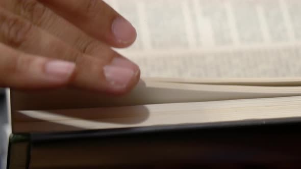 Close-up side view of a person turning the pages of a book