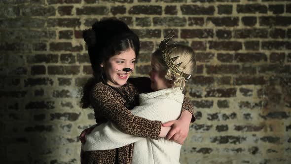 Two young girls in dressing up clothes, hugging