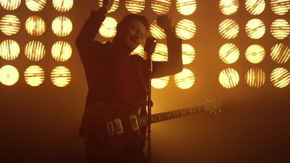 Guitarist Singing Microphone Enjoying Process at Spotlights