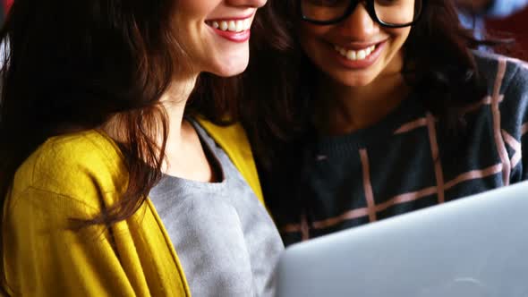 Smiling female executives discussing over laptop during meeting