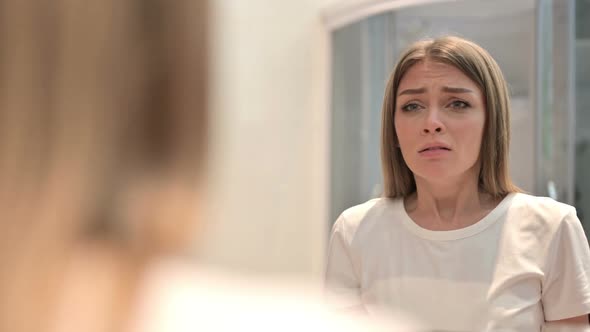 Rear View of Upset Young Woman Crying in the Mirror