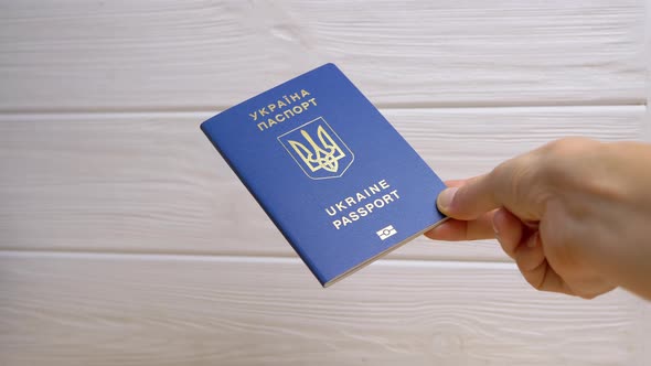 Woman Hand Holding a Blue Biometric Passport of Ukraine on White Background