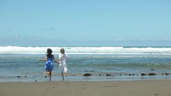 Couple holding hands and running to ocean