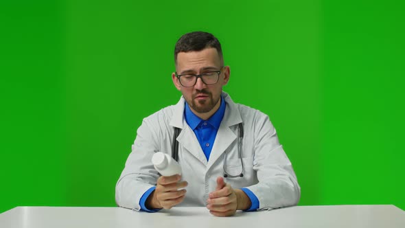 Male Doctor Holding a Bottle of Pills Promoting Them on Green Background