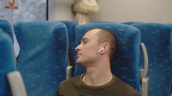 The Young Man Looks Out of the Train Window and Smiles Dreamily Then Returns to the Book