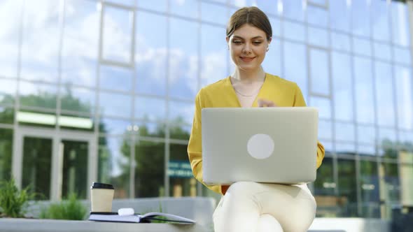 Focused Businesswoman Using Wireless Earphones Working on Laptop Computer Near Modern Office