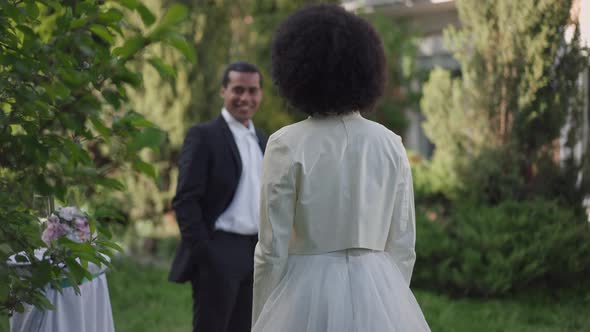 Back View of Unrecognizable African American Bride in Wedding Dress in Spring Garden with Blurred