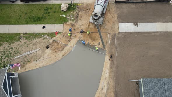 Cement truck backing up chute ready to release wet cement into the driveway forms.