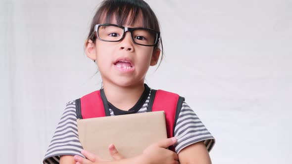 upset schoolgirl wearing casual clothes with backpack holding books