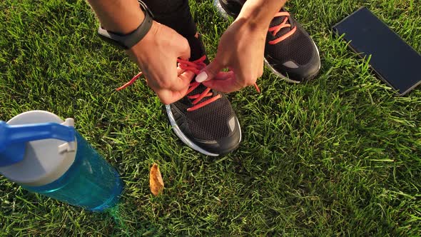 Fit Female Hands Tying Shoelaces Standing on Grass