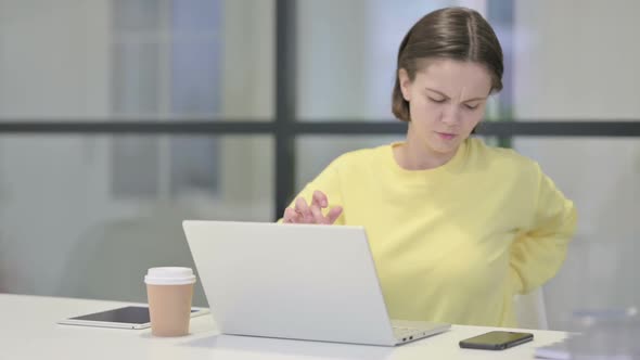 Young Woman Having Back Pain While Using Laptop in Office